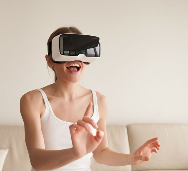 Excited young woman wearing VR headset touching virtual reality
